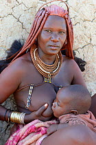 Himba woman with the typical ornaments nursing her baby. Kaokoland, Namibia October 2015