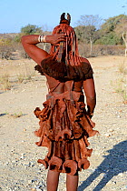 Himba woman with typical skirts made from goat skin covered in Otjize (a mixture of butter, ochre and ash) Kaokoland, Namibia. October 2015