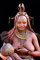 Himba woman with traditional hair and jewellery, nursing her baby. Kaokoland, Namibia October 2015