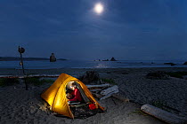 Moon rising over campsite, Toleak Point, Olympic National Park, Washington, USA. August 2015. Model released.