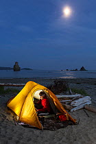 Moon rising over campsite, Toleak Point, Olympic National Park, Washington, USA. August 2015. Model released.