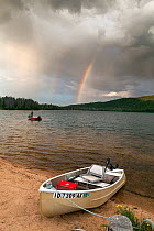 Doug Anderson fishing on Stanley Lake during rain shower, with rainbow, Stanley Lake National Recreation Area, Idaho, USA. July 2015. Model released.