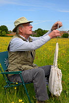 Colin Morris weighing a Kestrel chick( Falco tinnunculus) in a bag during a nestbox survey for the the Hawk and Owl Trust's Kestrel Highways project, Congresbury, Somerset, UK, June. Model released.
