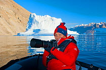 Portrait of photographer Olga Kamenskaya with camera equipment on small boat, Lake Baikal, Russia. August 2011.
