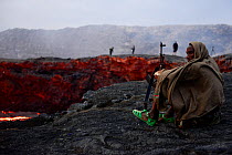 An armed soldier watching the activity of Erta Ale volcano crater at dawn. Afar Region, Ethiopia, Africa. November 2014.
