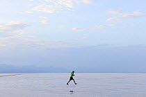 Person walking across Lake Assale, one of the largest salt lakes in Africa. Danakil Depression, Afar Region, Ethiopia, Africa. November 2014.