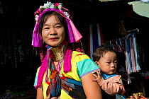 Kayan woman with neck rings and baby, Thailand. November 2015.