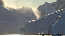 View of mountains and blowing snow, seen from a boat passing through Lemaire Channel, Antarctic Peninsula.