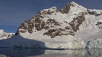 Tilt shot of a mountain and its reflection, seen from a boat passing through Lemaire Channel, Antarctic Peninsula.