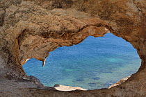 Eroded tunnel through a large volcanic rock, named 'Kalikatsou', above Petra beach, Patmos, Dodecanese Islands, Greece, August 2013.