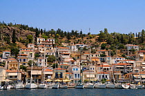 Sailing yacths moored on the quay at Poros town harbour viewed from the sea, Poros island, Attica, Peloponnese, Greece, August 2013.