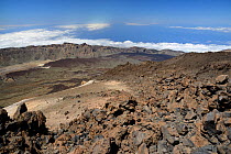 Overview of Las Canadas caldera from the 3700m summit of Mount Teide, the highest mountain in Europe, with old lava flows and pumice deposits, with clouds over the sea in the background, Tenerife, May...