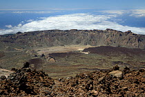 Overview of Las Canadas caldera from the 3718m summit of Mount Teide, the highest mountain in Spain, with old lava flows and pumice deposits, with clouds over the sea in the background, Tenerife, May.