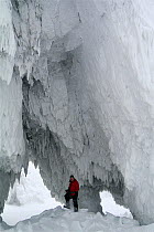 Sergey Gorshkov standing in ice cave in rock face, Wrangel Island, Far East Russia. March 2011.