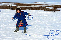 Young boy, Nenet herder practising lasso, wearing traditional malitsa coat. Yar-Sale district, Yamal, Northwest Siberia, Russia. April 2016.