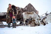 Nenet woman preparing for spring migration dressing herself and her son in traditional winter boots and coat made with reindeer skin. The temperature is below zero. Yar-Sale district, Yamal, Northwest...
