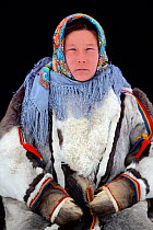 Ekaterina Yaptik, portrait of Nenet herder in winter coat made of reindeer fur. The collar is arctic fox fur with black beaver straps and felt ribbons. Yar-Sale district, Yamal, Northwest Siberia, Rus...