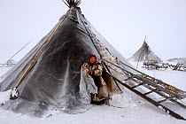 Nenet woman at entrance of tent in blizzard. Yar-Sale district. Yamal, Northwest Siberia, Russia. April  2016.