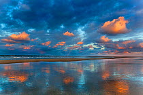Sunset on Holkham Beach, with clouds reflected in the water, Norfolk, England, UK, January.
