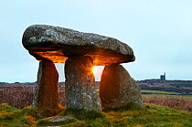 Sunrise casting rays through stones of Lanyon Quoit ancient  burial chamber, Madron, Cornwall, England, UK. February 2006.