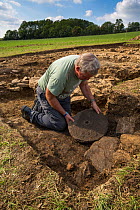 Archaeologist with quern stone at an excavation of a 2nd century Roman villa at Hanging Hill, Gloucestershire, UK. September 2015.
