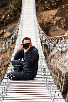 Photographer on footbridge, W Trek. Torres del Paine National Park, Patagonia, Chile. January 2014. Model released.