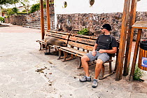 Galapagos sealion (Zalophus californianus wollebaeki) and man on benches. San Cristobal, Galapagos. Ecuador, November 2013.