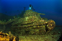 A diver above a tank laying on port side on the deck of the the wreck of the San Francisco Maru, a passenger cargo used as a auxiliary transport vessel, Chuuk or Truk Lagoon, Carolines Islands, Pacifi...