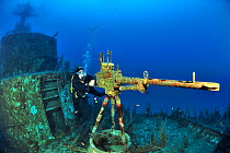A diver near the machine gun on the deck of the wreck of the P 29 a patrol boat scuttled as an artificial dive site in August 2007, Malta, Mediterranean