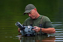 Wildlife Photographer Ingo Arndt preparing camera in underwater-housing to photograph European Beavers (Castor fiber) , Spessart, Germany, June.
