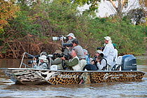 Tourists in boat on river photographing Jaguars. Cuiaba River. Porto Jofre, northern Pantanal, Mato Grosso State, Brazil. September