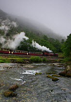 A steam train enters Aberglaslyn Pass, alongside the river Glaslyn, near Beddgelert, Wales, UK June