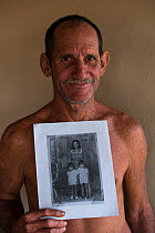 Tommy Kenyon, holding old family photograph, cowboy on Saddle Mountain (cattle) Ranch, Rurununi savanna, Guyana, South America