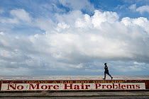 Man walking along sea wall, built by the Dutch as town is below sea level, Georgetown, Guyana, South America