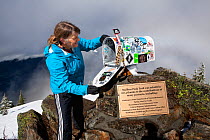 Woman looking inside the mailbox  on the summit of Mailbox Peak near North Bend, Washington, USA. March 2016. Model released.
