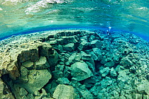 Scuba diver exploring Little Crack, almost like a miniature version of the main fissure, with both deep and shallow sections and many tunnels, Silfra Lagoon, Thingvellir National Park, Iceland.