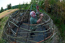 Artist finishing 'Siljustol', an artwork of living willow branches. Valer, Ostfold County, Norway. Jully 2014.  Model released.