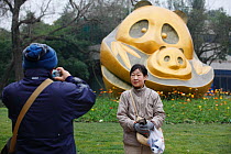 Tourist having photograph taken in front of sculpture of Giant panda in the Chengdu Panda Breeding Center, Sichuan, China, January 2012.