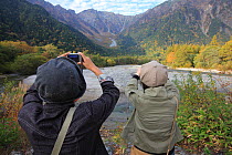 Japanese tourists in Japanese Alps, looking at autumn colors, Kamikochi Valley, Honshu, Japan.