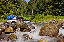 Off road vehicle fording a river, Arfak Mountains River Crossing, West Papua, August 2009.