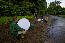 Eric Liner and Ian Fein interview ornithologist Edwin Scholes at the edge of the river in the lowland forest near Oransbari, West Papua, New Guinea.