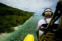 Max Ammer piloting his ultralight plane past Kri Eco Resort on Kri Island, West Papua, Indonesia.
