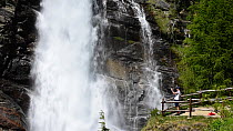 Tourist taking picture of waterfall at Lillaz, near Cogne, in the Aosta Valley, Gran Paradiso National Park in the Italian Alps, Italy, June