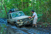4x4 drive stuck in the mud on the track to Nancite, The driver is using a winch to pull the vehicle out of the mud. Santa Rosa National Park, Costa Rica. November 2010.
