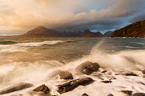 Waves crashing over rocky coastline near Elgol with view to Cuillin mountains, Isle of Skye, Scotland