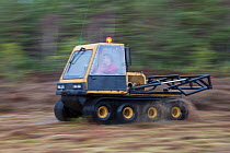 Person driving machine as part of peatland restoration project. Moss brash will be distributed on to bare peat, Inshriach, Glenfeshie, Cairngorms National Park, Scotland, UK, January 2015.