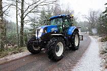 Tractor transporting bags of moss brash to distribute on bare peat as part of peatland restoration project, Inshriach, Glenfeshie, Cairngorms National Park, Scotland, UK, January 2015.