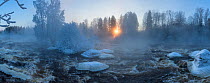 Sunrise over frozen river and forest Kuusaa, Finland, January.
