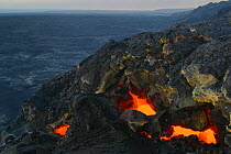 Skylights in the roof of a lava tube reveal the red hot liquid lava travelling through the tube toward the ocean from Kilauea Volcano, Hawaii Volcanoes National Park, Ka'u, Hawaii, USA, March 2003
