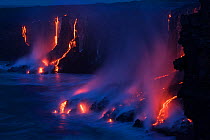 Hot lava from the 61G flow, emanating from Pu'u O'o on Kilauea Volcano, flows over sea cliffs into the ocean at the Kamokuna ocean entry in Hawaii Volcanoes National Park, Kalapana, Puna, Hawaii, USA...